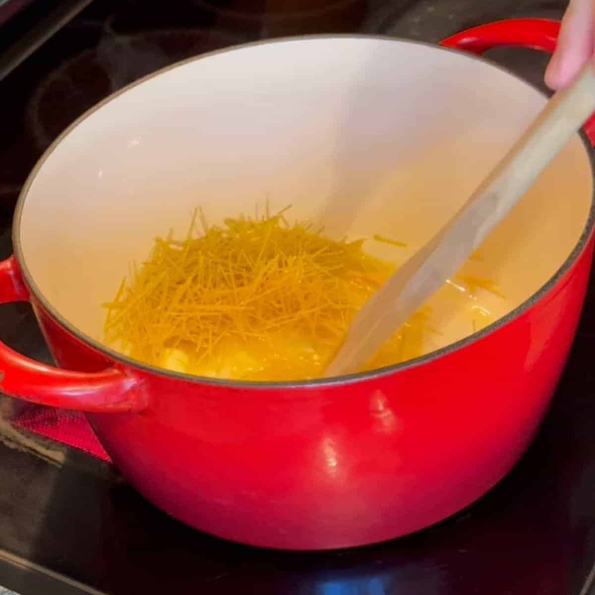 Dutch oven showing angel hair pasta browning in butter