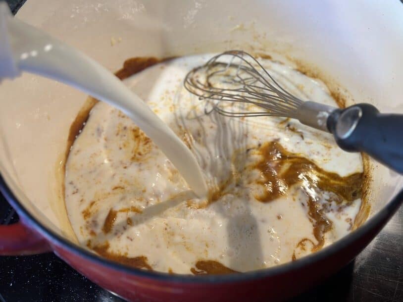 Whisking milk into a roux while making stovetop mac and cheese