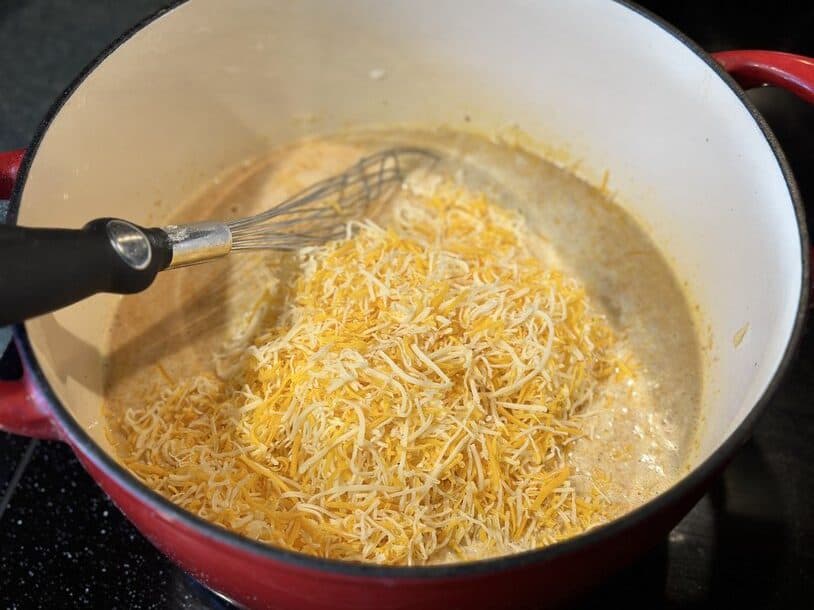 Shredded cheese added to a pot while making mac and cheese