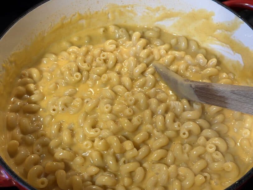 Creamy stovetop mac and cheese in a pot with a wooden spoon