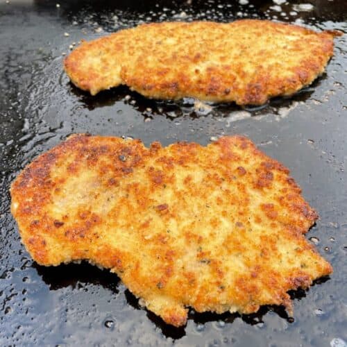 Breaded chicken cutlets cooking on a Blackstone griddle